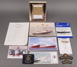 Two Royal Yacht Britannia embroidered cloth shoulder titles, a menu card 1977 for the Pool of London, photograph frame containing a section of gold leaf used to repair band around the hole