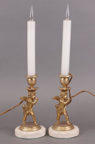 A pair of gilt ormolu candlesticks in the form of standing cherubs, raised on marble bases 20cm h, (converted to electric lights) 