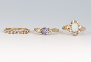 A 9ct gold half eternity ring set white stones, a 9ct ring set two diamonds and a pale blue stone, together with an opal set ring surrounded by white stones, sizes K 1/2, L and K 1/2, gross weight 5g