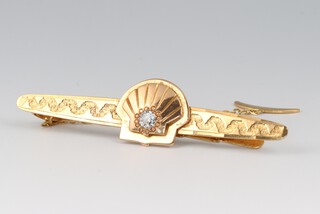 A gold marked 750 tie clip with Shell motif to the front set a diamond, 6cm wide, with safety chain, 9.5g gross