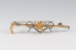 A gilt and white metal brooch in the form of a riding whip with foxes mask and bit 5cm wide
