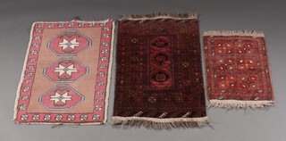 A brown, red and black ground Afghan slip rug with 3 medallions to the centre 89cm x 53cm, 1 other formed of 6 square floral panels 59cm x 40cm and a pink, blue and white slip rug with 3 diamonds to the centre 88cm x 55cm (3)