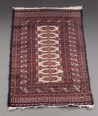 A blue, white and red Bukhara rug with 8 rectangular stylised medallions to the centre within a multi row border 134cm x 76cm 