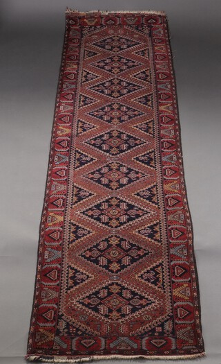 A red and blue ground Hamadan runner with 9 diamond medallions to the centre within a multi row border 295cm x 78cm 