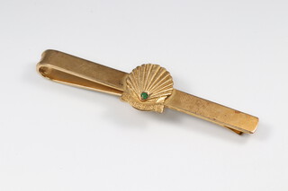 A 9ct gold tie clip set the Shell motif with inset green stone and marked 20 Years Service, 6cm wide, 8.4g